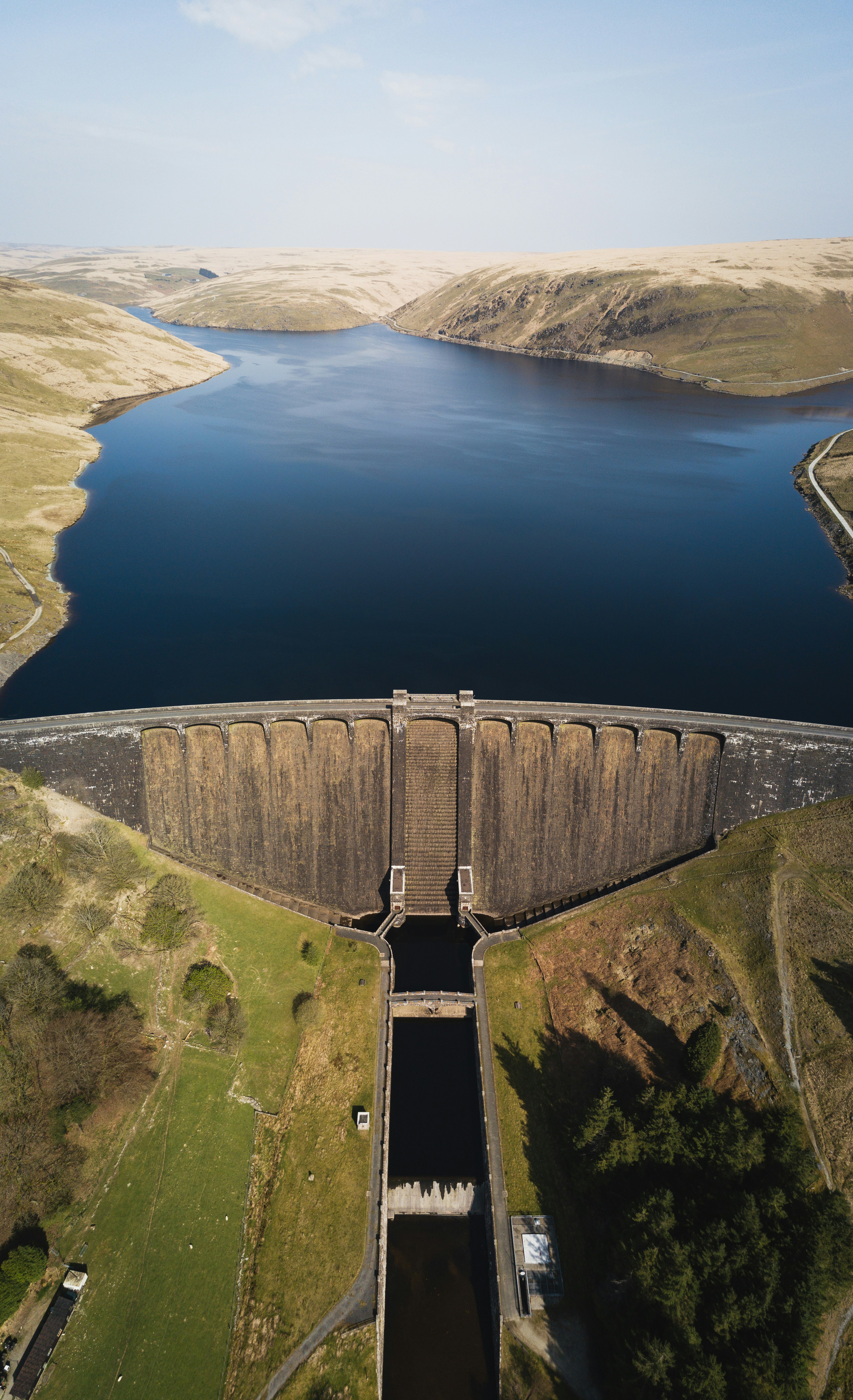 a dam with a lake and rolling hills as the shore. no water is being released.